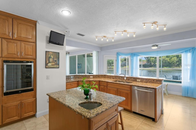 kitchen with crown molding, brown cabinets, appliances with stainless steel finishes, and a sink