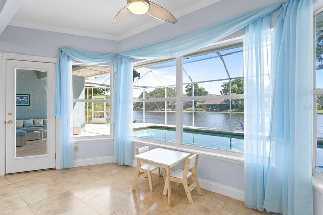 sunroom featuring a ceiling fan, plenty of natural light, and a water view