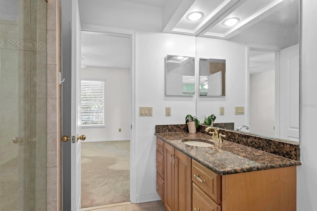 full bath with baseboards, tiled shower, and vanity