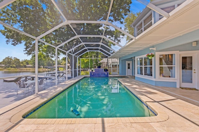 outdoor pool with glass enclosure, a patio, and a water view