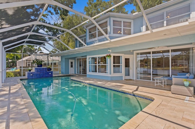 back of house featuring glass enclosure, an outdoor pool, a patio area, and stucco siding