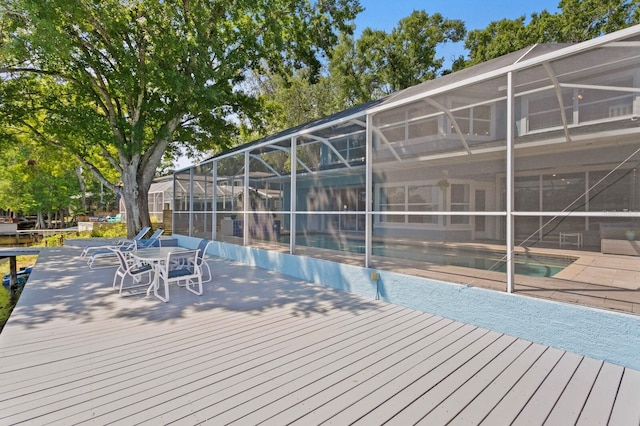 deck featuring outdoor dining area, an outdoor pool, and a lanai