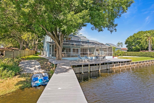 dock area with a water view, glass enclosure, and fence