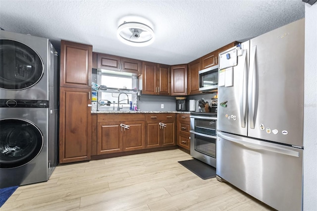 5304 Cherry Ave, Seffner, FL 33584 - kitchen featuring stacked washer and dryer, a textured ceiling, appliances with stainless steel finishes, light stone countertops, and light wood-style flooring