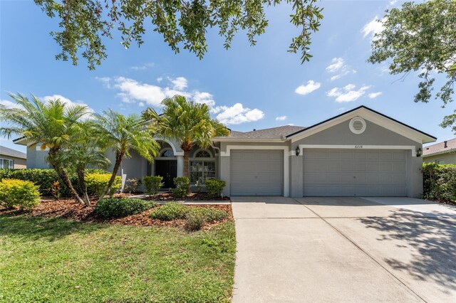 single story home with a garage, stucco siding, driveway, and a front lawn