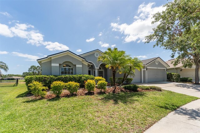 single story home with a garage, a front lawn, fence, stucco siding, and driveway