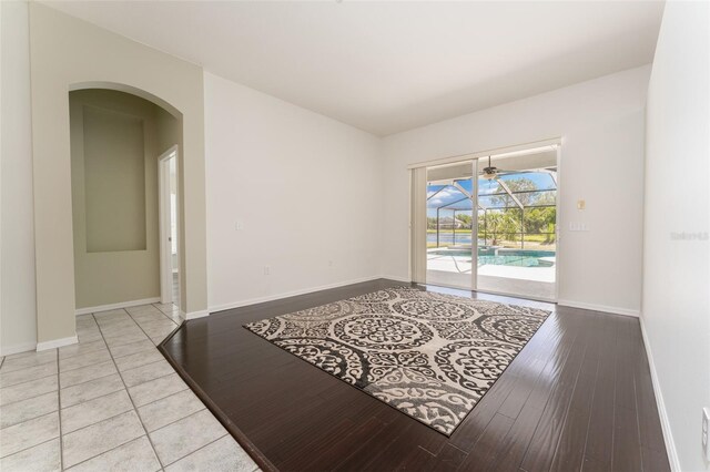 empty room with arched walkways, baseboards, and wood finished floors