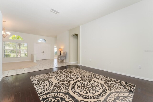 foyer featuring a notable chandelier, arched walkways, baseboards, wood finished floors, and visible vents