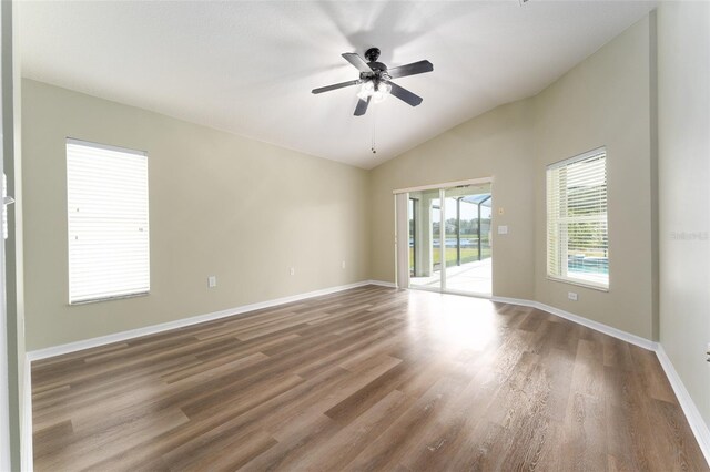 empty room featuring a ceiling fan, baseboards, vaulted ceiling, and wood finished floors