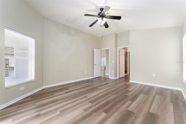 spare room featuring baseboards, ceiling fan, wood finished floors, and vaulted ceiling