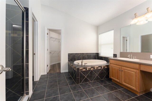 bathroom featuring tile patterned flooring, a garden tub, vanity, a walk in closet, and a shower stall