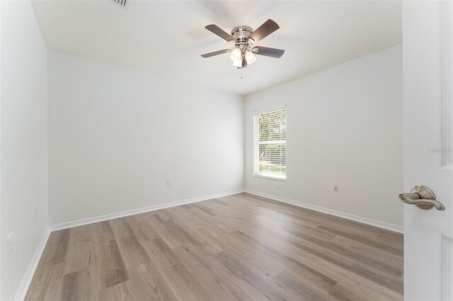 unfurnished room with a ceiling fan, baseboards, and light wood-style flooring