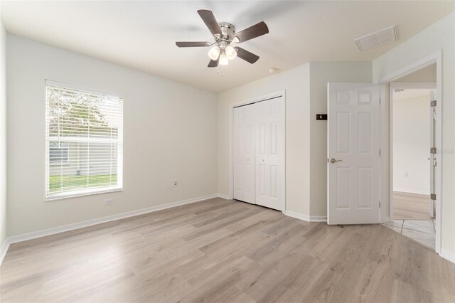 unfurnished bedroom featuring light wood finished floors, a ceiling fan, baseboards, visible vents, and a closet