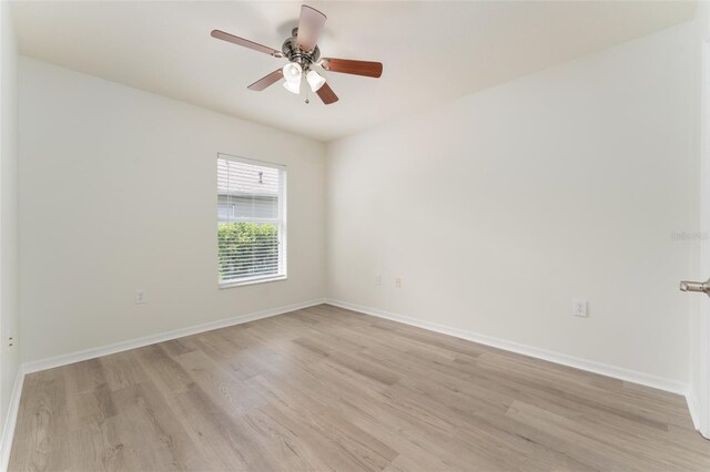 empty room with light wood-style floors, a ceiling fan, and baseboards