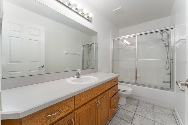 bathroom featuring visible vents, vanity, tile patterned floors, toilet, and shower / bath combination with glass door