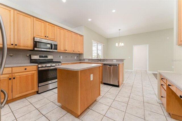 kitchen with a kitchen island, light countertops, a sink, an inviting chandelier, and stainless steel appliances