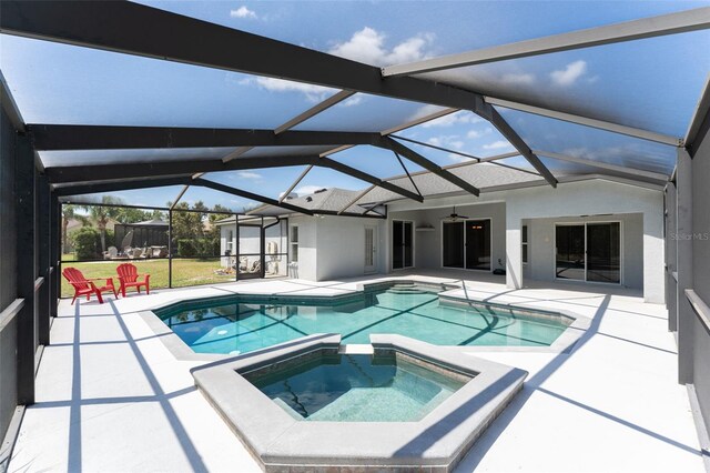 view of swimming pool featuring a patio, ceiling fan, a pool with connected hot tub, and glass enclosure