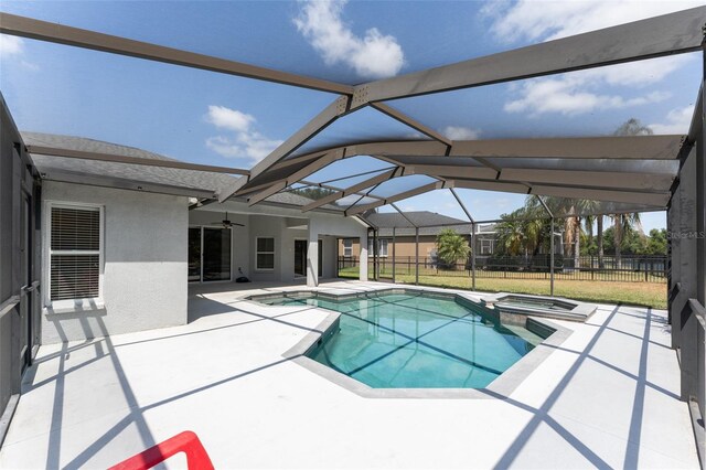view of pool with fence, a pool with connected hot tub, a patio area, a ceiling fan, and a lanai