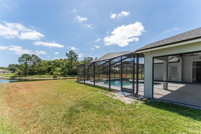 view of yard featuring ceiling fan, an outdoor pool, a water view, a patio area, and glass enclosure