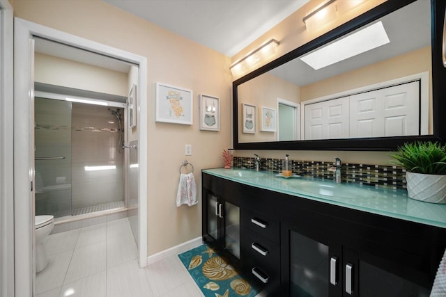 bathroom featuring a sink, baseboards, a skylight, and toilet