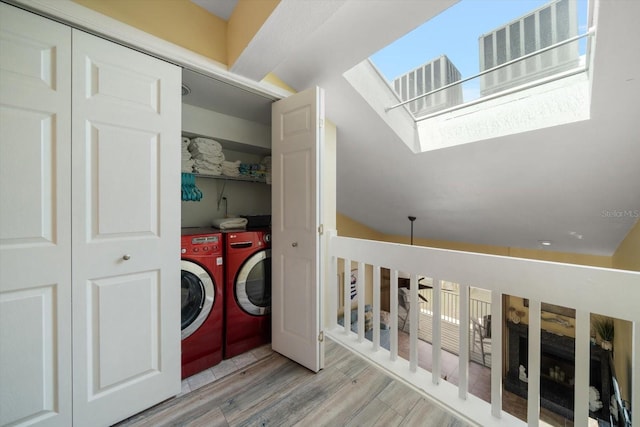 laundry area featuring independent washer and dryer, laundry area, a skylight, and wood finished floors
