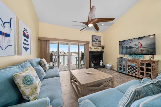 living room featuring tile patterned flooring, a ceiling fan, a fireplace with raised hearth, and lofted ceiling