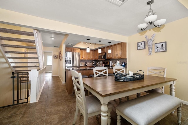dining area with dark tile patterned flooring, baseboards, visible vents, and a chandelier