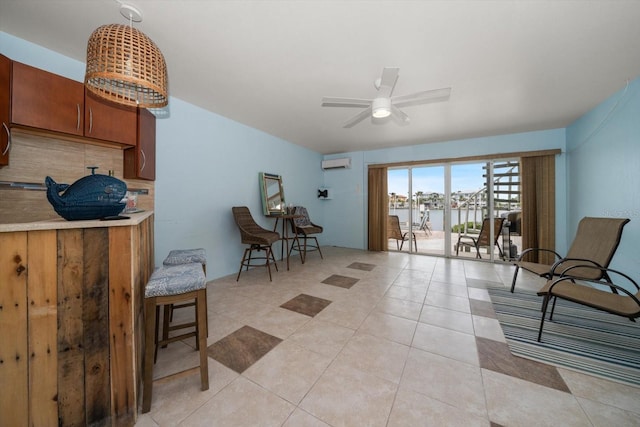 sitting room with light tile patterned floors, a water view, a ceiling fan, and a wall mounted air conditioner