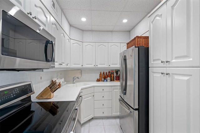 kitchen featuring stainless steel appliances, a sink, white cabinets, a drop ceiling, and recessed lighting