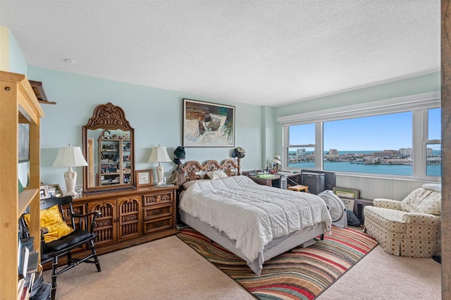 carpeted bedroom featuring a textured ceiling and a water view