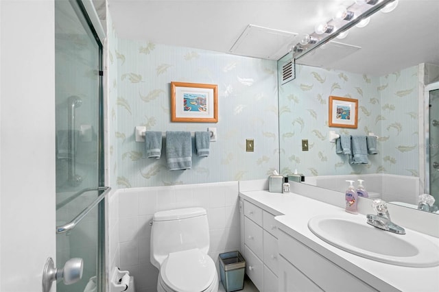 bathroom with wainscoting, vanity, toilet, wallpapered walls, and a shower stall