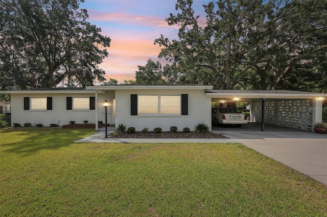 single story home with concrete driveway, a yard, and a carport