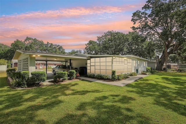 back of house at dusk with a yard and an attached carport