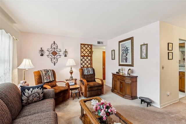 living area with baseboards, visible vents, and light colored carpet