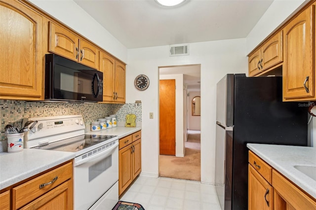 kitchen with freestanding refrigerator, visible vents, black microwave, light countertops, and electric stove