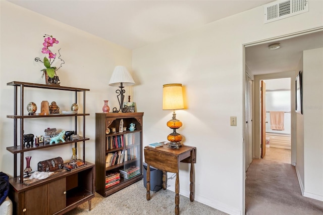 hall featuring baseboards, visible vents, and speckled floor