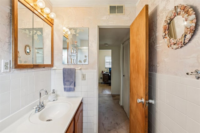 bathroom with tile walls, visible vents, vanity, and a wainscoted wall