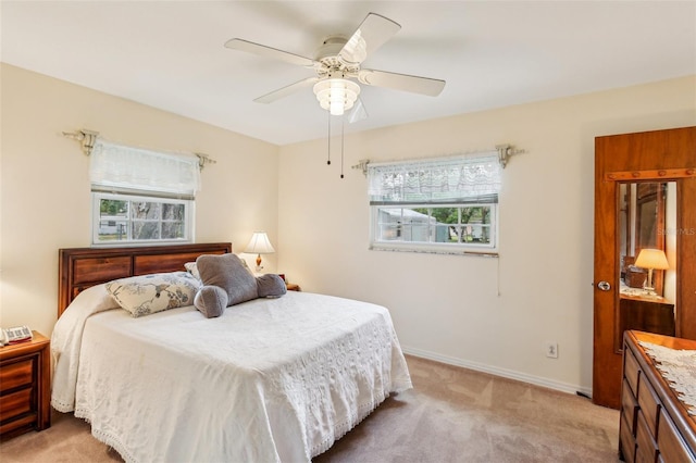 bedroom featuring light colored carpet, baseboards, and a ceiling fan