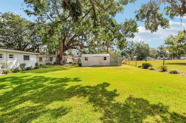 view of yard with a storage shed, an outdoor structure, and fence