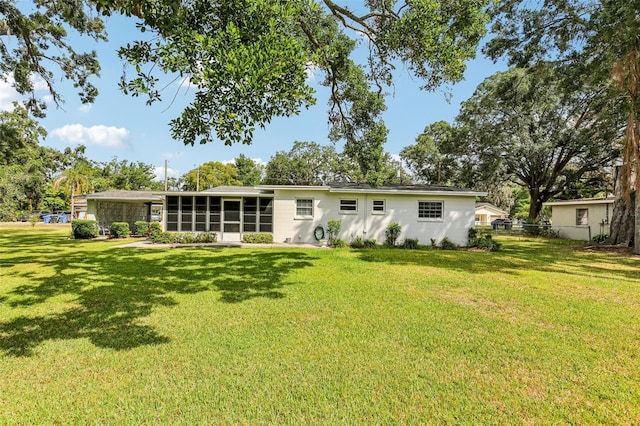 rear view of property featuring a lawn, a sunroom, and fence