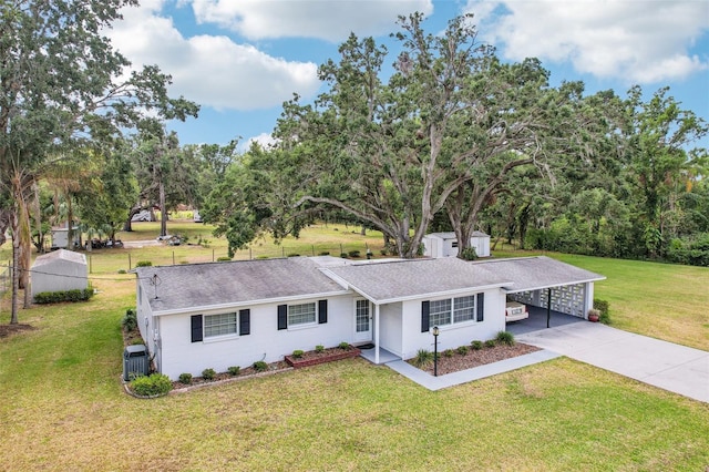 ranch-style home featuring cooling unit, a shingled roof, concrete driveway, a front lawn, and a carport