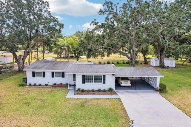 single story home with driveway, an attached carport, roof with shingles, and a front yard