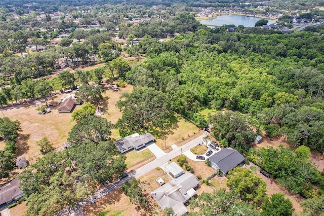 birds eye view of property featuring a water view and a wooded view