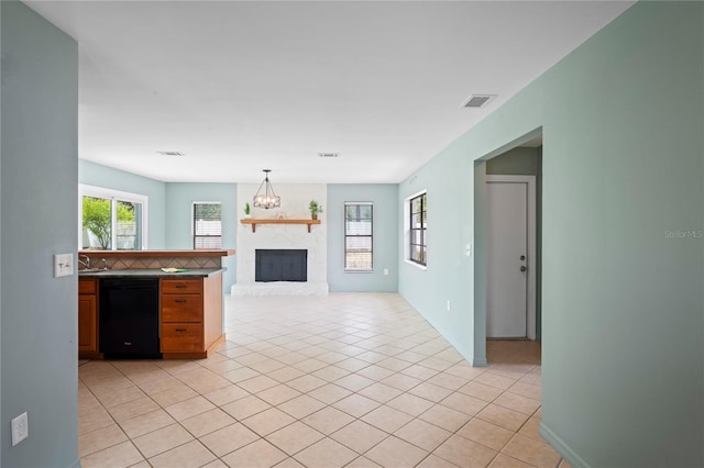 3353 Montano Ave, Spring Hill, FL 34609 - kitchen featuring light tile patterned floors, black dishwasher, open floor plan, visible vents, and a large fireplace