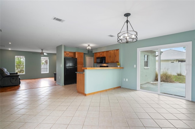3353 Montano Ave, Spring Hill, FL 34609 - kitchen with brown cabinetry, visible vents, a peninsula, open floor plan, and black appliances