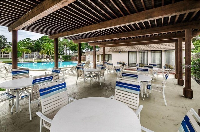 view of patio with a community pool, fence, and outdoor dining area