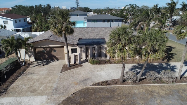2015 Dolphin Blvd S, Saint Petersburg, FL 33707 - view of front of house with concrete driveway, an attached garage, solar panels, and stucco siding