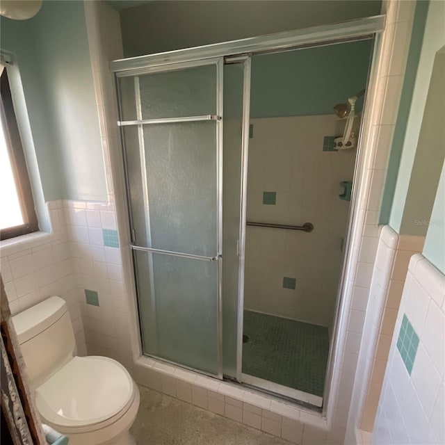 2015 Dolphin Blvd S, Saint Petersburg, FL 33707 - bathroom featuring toilet, tile walls, a shower stall, and a wainscoted wall