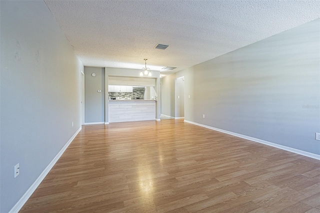unfurnished room featuring visible vents, light wood-style flooring, and a textured ceiling