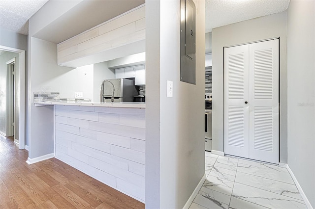 kitchen featuring a textured ceiling, fridge, light countertops, baseboards, and marble finish floor